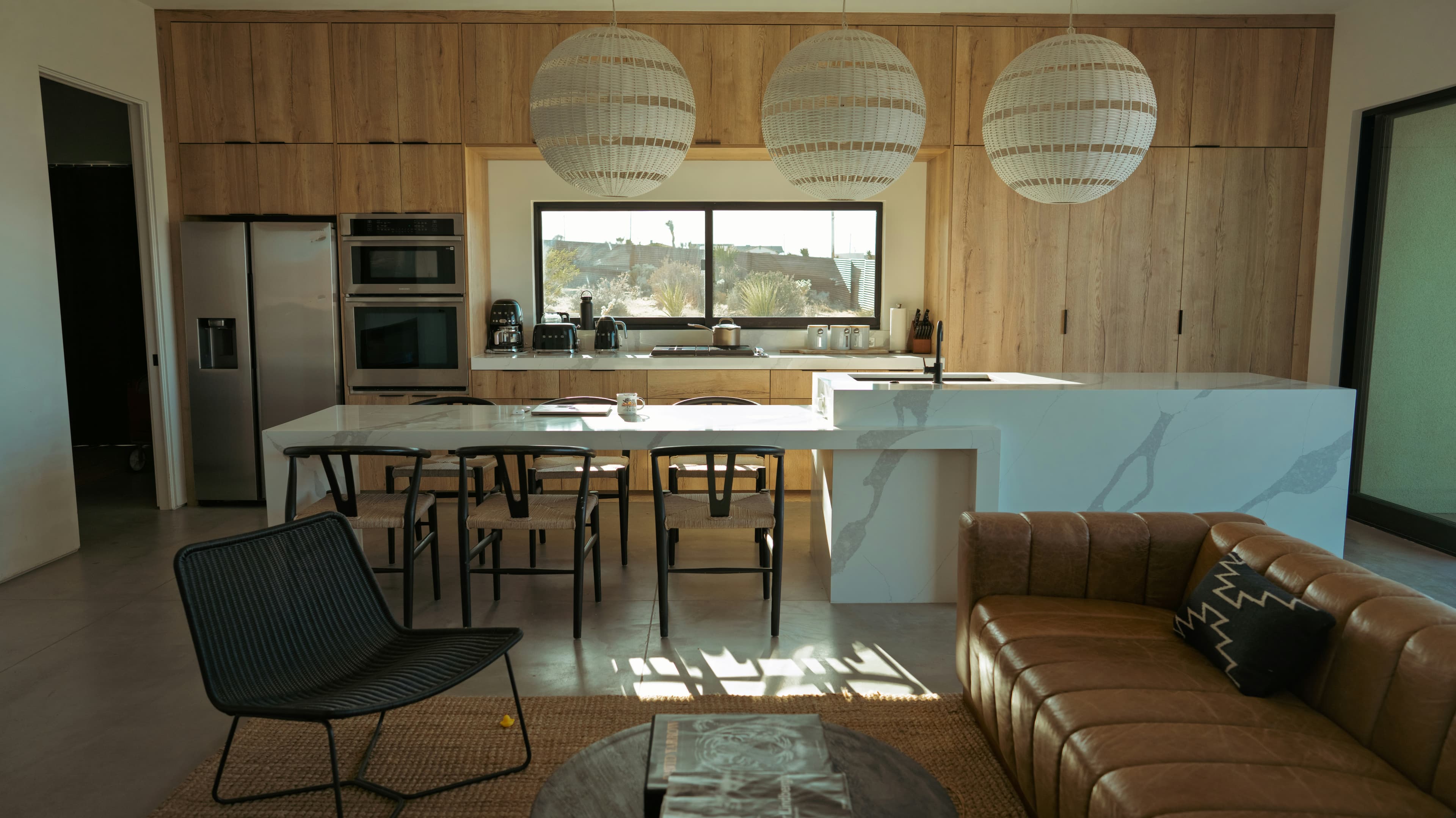Warm wood kitchen cabinets with a stone island and woven pendant lights